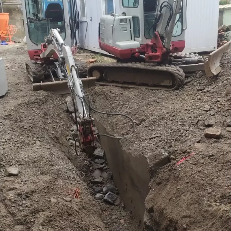 Zwei Bagger in der Nähe eines ausgehobenen Grabens bei Erdarbeiten auf einer Baustelle.